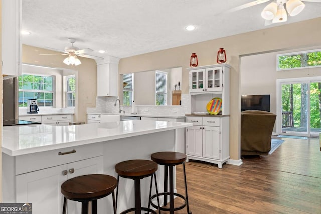 kitchen featuring a ceiling fan, a wealth of natural light, white cabinetry, and a kitchen breakfast bar