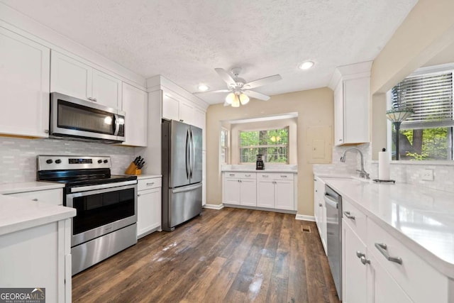 kitchen with white cabinets, a sink, tasteful backsplash, light countertops, and appliances with stainless steel finishes