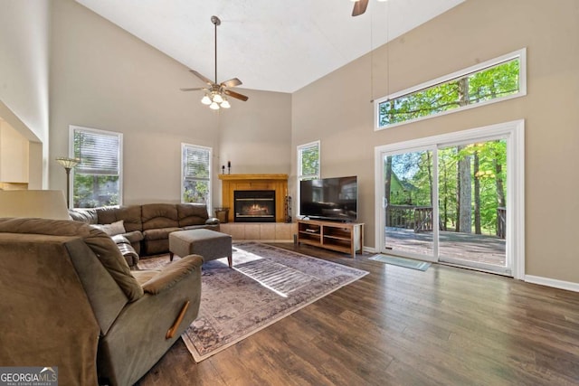living room with wood finished floors, a ceiling fan, a high ceiling, and a healthy amount of sunlight