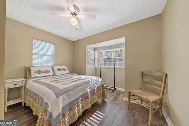 bedroom with ceiling fan, baseboards, dark wood-type flooring, and a textured ceiling