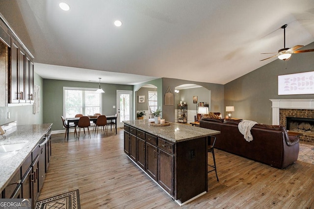 kitchen featuring ceiling fan, open floor plan, and light wood-style flooring