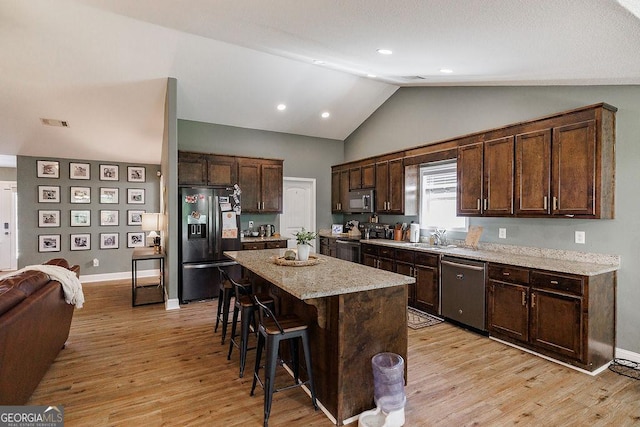 kitchen with a breakfast bar, dark brown cabinets, light wood-style floors, and appliances with stainless steel finishes