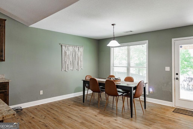 dining room with light wood-style flooring, visible vents, and baseboards