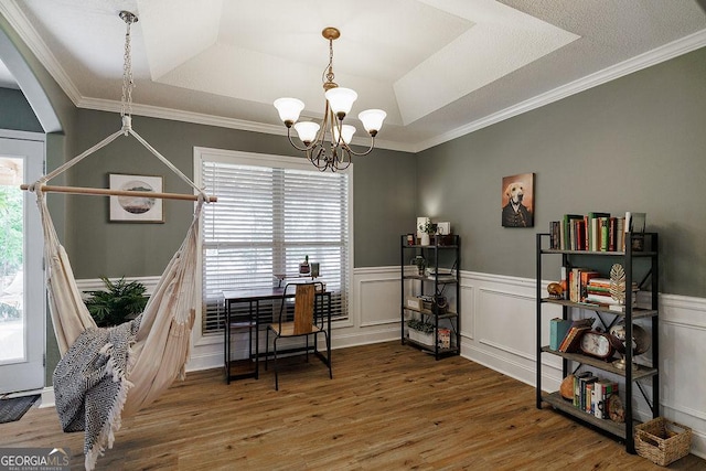 office space with a raised ceiling, a healthy amount of sunlight, and a notable chandelier