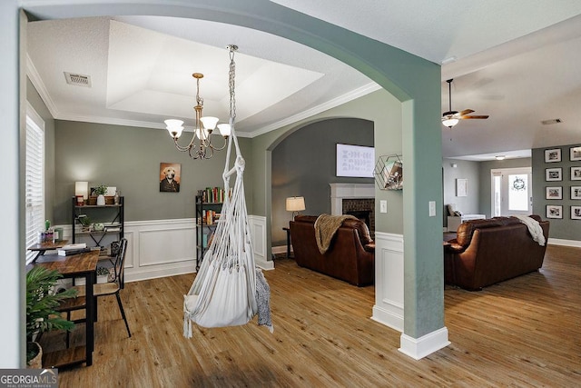 dining area featuring visible vents, ceiling fan with notable chandelier, wood finished floors, a fireplace, and a raised ceiling
