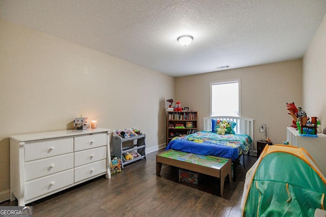 bedroom with dark wood finished floors, baseboards, a textured ceiling, and visible vents