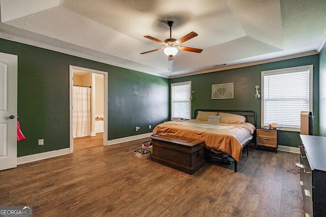 bedroom with a raised ceiling, wood finished floors, crown molding, and multiple windows