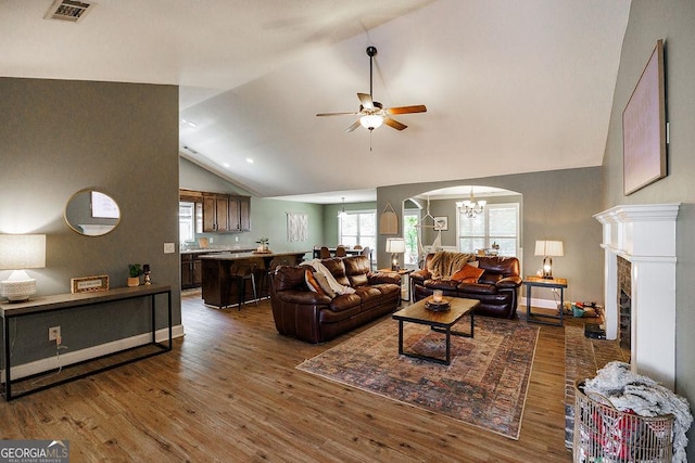 living room with wood finished floors, vaulted ceiling, visible vents, and ceiling fan with notable chandelier