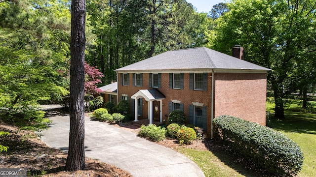 view of front facade featuring brick siding and a chimney