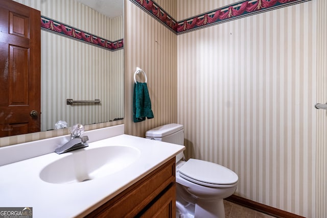bathroom with wallpapered walls, vanity, baseboards, toilet, and tile patterned flooring