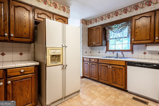 kitchen featuring a sink, tasteful backsplash, visible vents, white appliances, and light floors