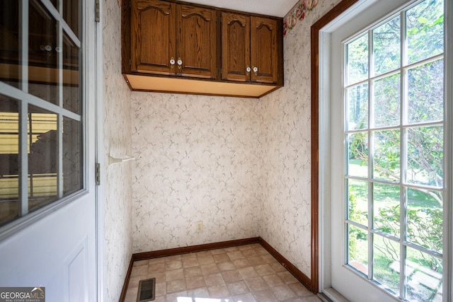interior space featuring a wealth of natural light, wallpapered walls, visible vents, and baseboards