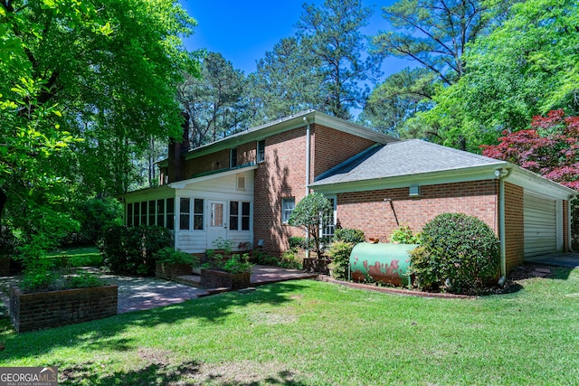 back of house with a sunroom, heating fuel, a yard, and brick siding