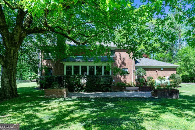 back of property featuring brick siding and a yard