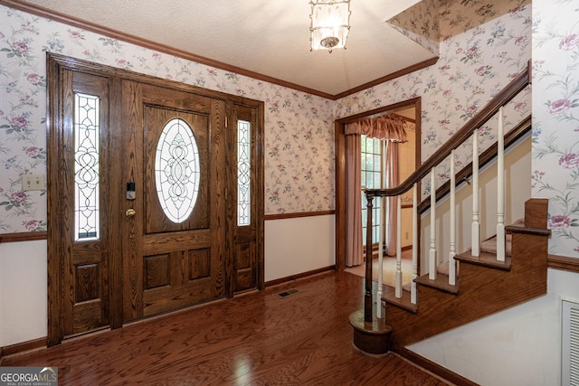 foyer with stairway, wood finished floors, visible vents, ornamental molding, and baseboards