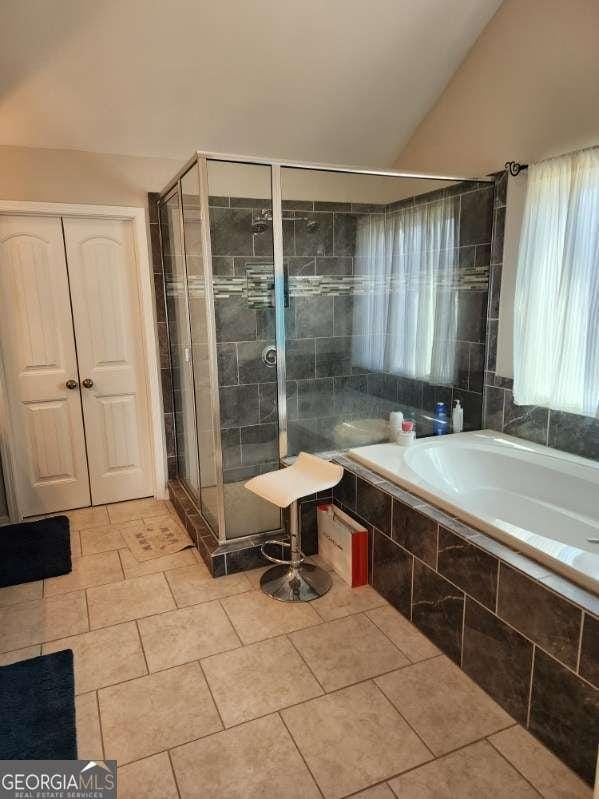 134 Sierra Cir, Woodstock, GA 30188 - full bath featuring tile patterned floors, tiled tub, vaulted ceiling, and a shower stall