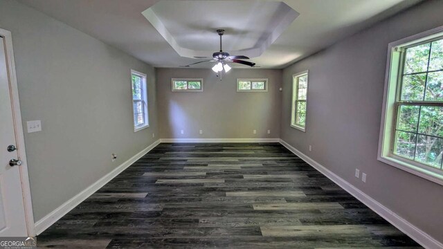 685 Greenhedge Dr, Stone Mountain, GA 30088 - empty room featuring a tray ceiling, dark wood-type flooring, healthy amount of natural light, and ceiling fan