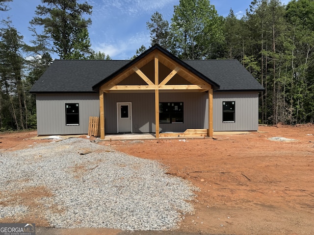 view of front facade featuring roof with shingles and a porch