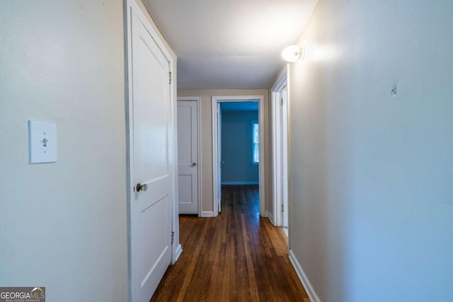 hallway with dark wood-style flooring and baseboards