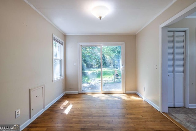 unfurnished dining area with hardwood / wood-style flooring, ornamental molding, and baseboards