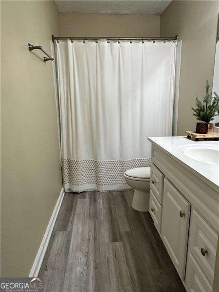 6630 Crystal Cove Trl, Gainesville, GA 30506 - full bathroom with a textured ceiling, toilet, wood finished floors, curtained shower, and vanity