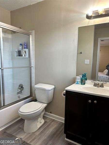 6630 Crystal Cove Trl, Gainesville, GA 30506 - bathroom with shower / bath combination with glass door, toilet, baseboards, wood finished floors, and vanity