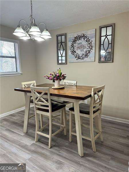 6630 Crystal Cove Trl, Gainesville, GA 30506 - dining room with light wood-type flooring, baseboards, an inviting chandelier, and a textured ceiling