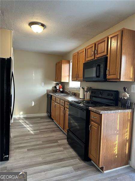 6630 Crystal Cove Trl, Gainesville, GA 30506 - kitchen featuring black appliances, brown cabinets, dark countertops, and light wood-style flooring