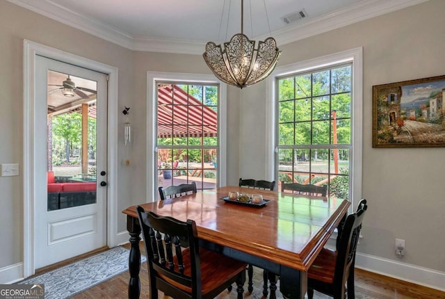 dining room with wood finished floors, visible vents, ornamental molding, baseboards, and a chandelier