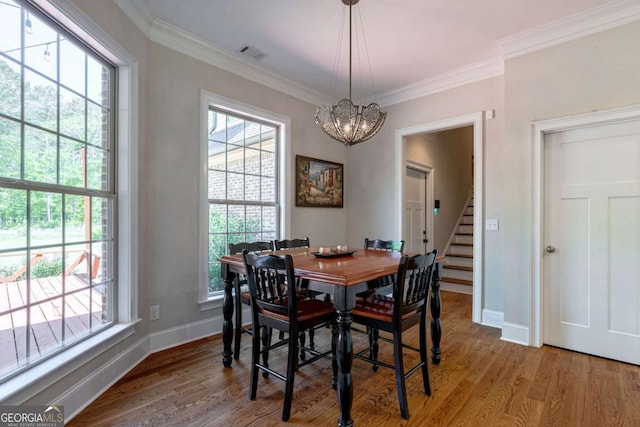 dining area with light wood-style flooring, a notable chandelier, and crown molding