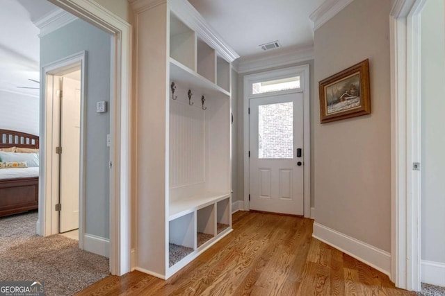mudroom with baseboards, crown molding, light wood finished floors, and visible vents