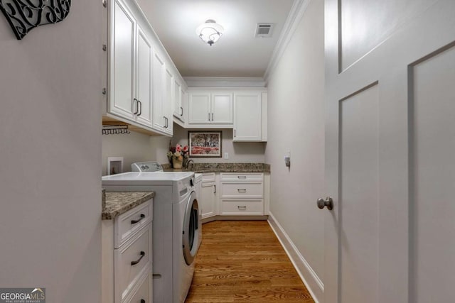 clothes washing area with light wood-style floors, cabinet space, washing machine and dryer, ornamental molding, and visible vents