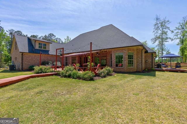 rear view of house featuring a gazebo, a yard, a wooden deck, brick siding, and ceiling fan