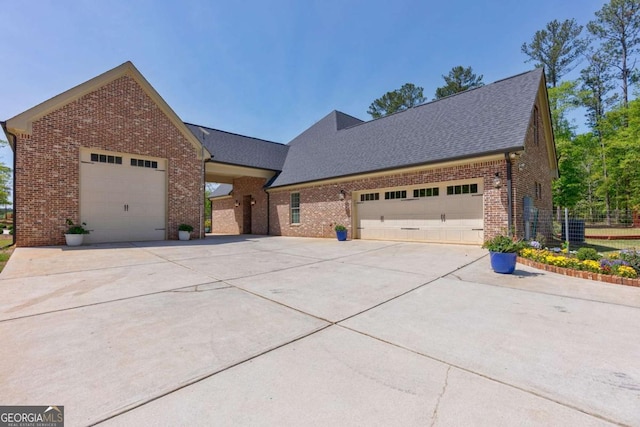 view of front of home featuring a shingled roof, driveway, brick siding, and a garage