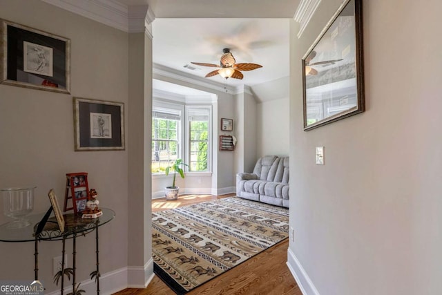 interior space featuring visible vents, wood finished floors, baseboards, and ornamental molding