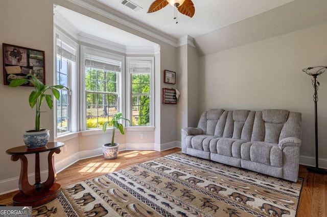 living room featuring baseboards, wood finished floors, visible vents, and crown molding