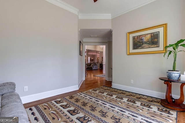 interior space featuring wood finished floors, baseboards, and ornamental molding