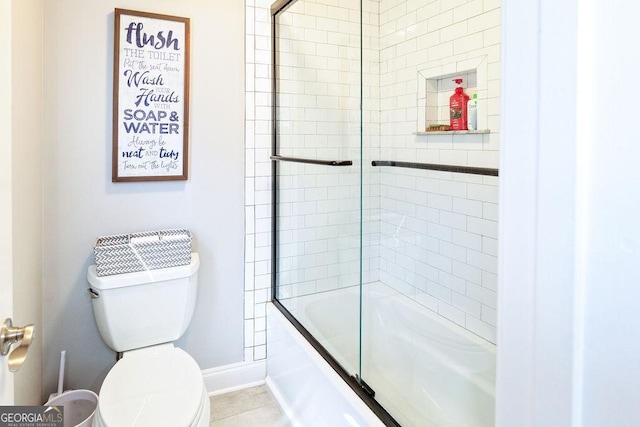 bathroom with toilet, shower / bath combination with glass door, and baseboards