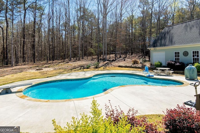 outdoor pool with a diving board, fence, and a patio area
