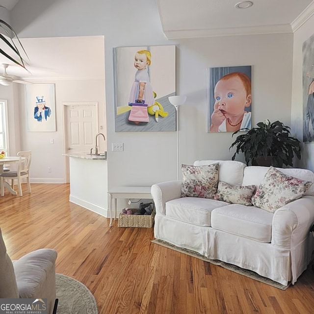 living room with crown molding, baseboards, and light wood-style floors