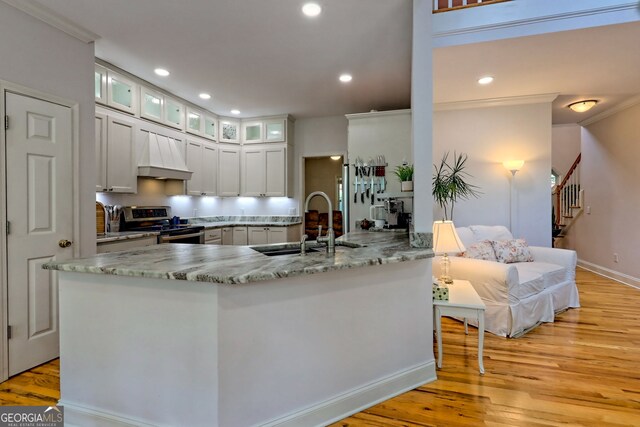 327 Kissimmee Trl, Cornelia, GA 30531 - kitchen with stainless steel electric range oven, custom range hood, light wood-style floors, a sink, and glass insert cabinets