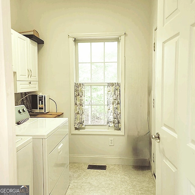 washroom featuring visible vents, baseboards, washer and clothes dryer, cabinet space, and a wealth of natural light