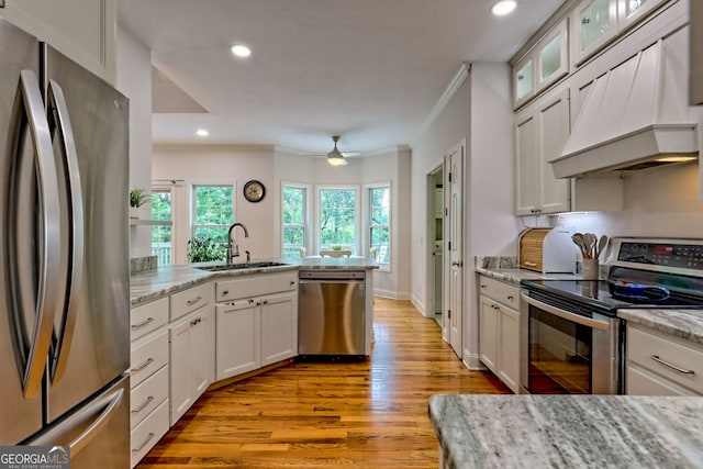 327 Kissimmee Trl, Cornelia, GA 30531 - kitchen with appliances with stainless steel finishes, custom range hood, crown molding, a sink, and light wood-style floors