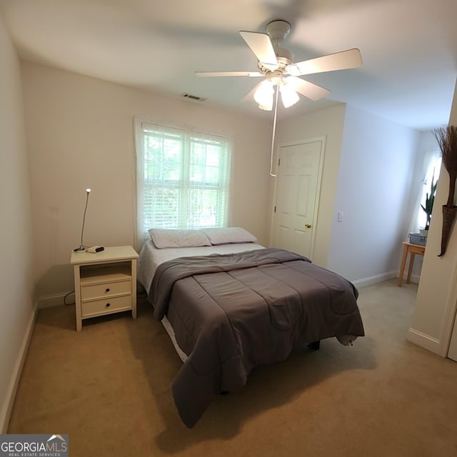 bedroom with visible vents, baseboards, ceiling fan, and light carpet