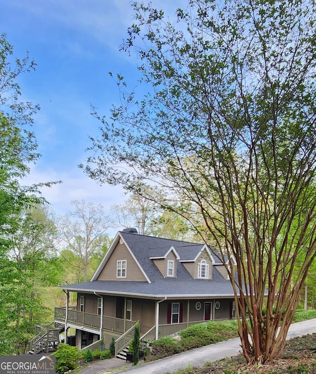 view of front of property featuring stairs, a shingled roof, and a porch