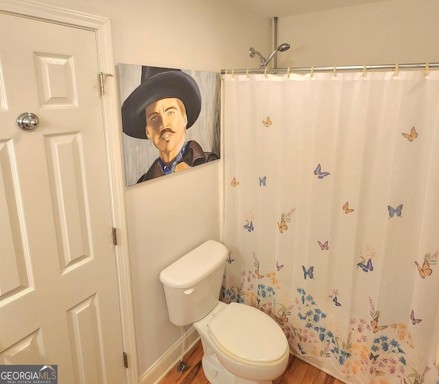 bathroom with a shower with shower curtain, toilet, and wood finished floors