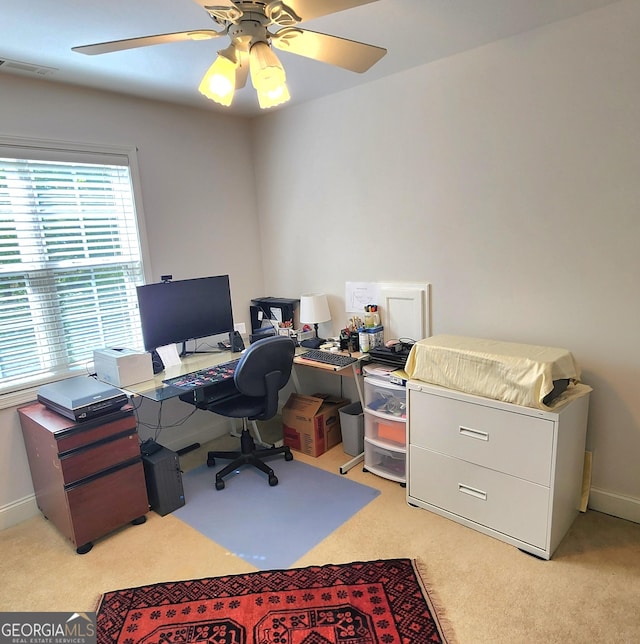 office space with visible vents, baseboards, ceiling fan, and light carpet