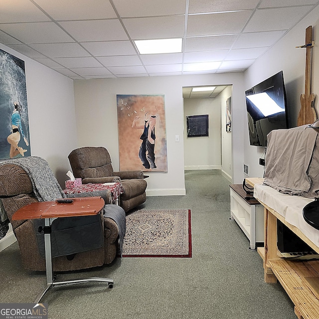 living room featuring carpet floors, baseboards, and a paneled ceiling