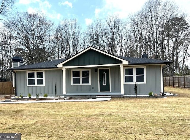 ranch-style house with a chimney, fence, board and batten siding, a porch, and a front yard