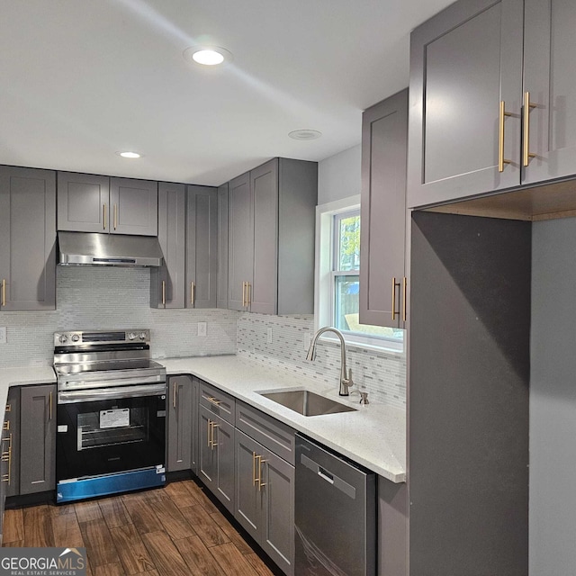kitchen featuring tasteful backsplash, a sink, appliances with stainless steel finishes, under cabinet range hood, and gray cabinetry